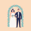 Happy cute newlywed couple standing against floral arch. Adorable bride and groom isolated on light background. Wedding Royalty Free Stock Photo