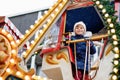 Happy cute preschool girl riding on ferris wheel carousel horse at Christmas funfair or market, outdoors. Little toddler Royalty Free Stock Photo