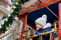 Happy cute preschool girl riding on ferris wheel carousel horse at Christmas funfair or market, outdoors. Little toddler