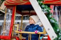 Happy cute preschool girl riding on ferris wheel carousel horse at Christmas funfair or market, outdoors. Little toddler