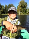 Happy cute schoolboy enjoyed the fishing. In his hands a small pike.boy is in rubber inflatable boat.Outside shot Royalty Free Stock Photo