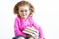 Happy cute smart little girl in funny big glasses reading a stack of paper books Royalty Free Stock Photo