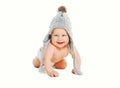 Happy cute smiling baby in knitted grey hat crawls on white