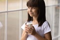 Happy cute thoughtful girl drinking milk, holding glass