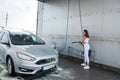 Happy cute woman cleans her car with high-pressure water gun Royalty Free Stock Photo