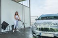 Happy cute woman cleans her car with high-pressure water gun Royalty Free Stock Photo