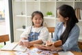 A happy young Asian girl is enjoying studying English with a teacher at home Royalty Free Stock Photo