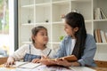 A happy young Asian girl is enjoying studying English with a teacher at home Royalty Free Stock Photo