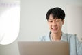 Happy cute young Asian man working on his business tasks on laptop computer at home Royalty Free Stock Photo