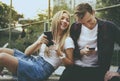 Happy cute young couple in the park using smartphones together