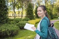 Happy cute young girl reading a book in the park. Side view