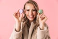 Happy cute young pretty woman posing isolated over pink wall background holding cake macaroons sweeties Royalty Free Stock Photo