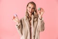 Happy cute young pretty woman posing isolated over pink wall background holding cake macaroons sweeties