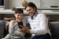 Happy dad and cheerful teen kid using, sharing smartphone together Royalty Free Stock Photo