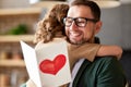 Happy dad getting congratulations from his cute daughter on Fathers day, holding greeting postcard Royalty Free Stock Photo