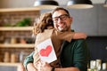 Happy dad getting congratulations from his cute daughter on Fathers day, holding greeting postcard