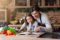 Happy dad and little daughter checking recipe in cookbook together