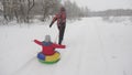 Happy dad sledges a child on a snowy road. Christmas Holidays. father plays with his daughter in a winter park. The