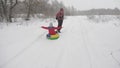Happy dad sledges a child on a snowy road. Christmas Holidays. father plays with his daughter in a winter park. The