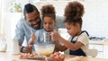 Happy dad teaching two cute preschooler kids to bake