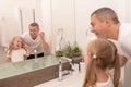 Dad teaches daughter to brush teeth with toothbrush and toothpaste in bathroom Royalty Free Stock Photo