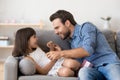 Happy daddy and cute daughter play together tickling on sofa