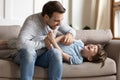 Happy daddy resting on sofa, tickling laughing little son. Royalty Free Stock Photo