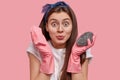 Happy dark haired woman cares of sanitary and hygiene, wears rubber gloves, holds two mops in hands, prepares to clean Royalty Free Stock Photo