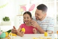 Happy daughter with bunny ears headband and her father having fun while painting Easter egg Royalty Free Stock Photo