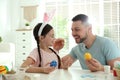 Happy daughter with bunny ears headband and her father having fun while painting Easter eggs Royalty Free Stock Photo