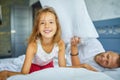 Happy daughter and father playing pillow fight in bed at morning at home