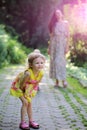 Happy daughter girl with blond curly hair walk with mother