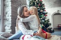 Happy daughter kissing her mother over christmas tree lights background Royalty Free Stock Photo