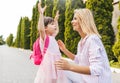 Happy daughter little girl and pretty mother embracing each other on sidewalk on the street. Mom met the child after the