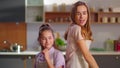 Happy daughter and mother dancing back to back on kitchen in slow motion