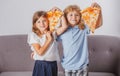 Happy daughter and son eating pizza. Children kids enjoy and having fun with lunch together at home. Funny children Royalty Free Stock Photo