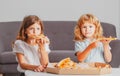 Happy daughter and son eating pizza. Children kids enjoy and having fun with lunch together at home. Little friends, boy Royalty Free Stock Photo