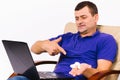 Happy deaf senior man with a laptop shows his forefinger at the hearing aid. White background. Royalty Free Stock Photo