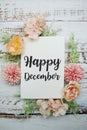 Happy December text on paper card with flowers frame on wooden background