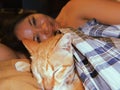 Happy defocused female person sleeping with cat in bed. Relaxation at home with pet. Ginger cat lying near human. Soft Royalty Free Stock Photo