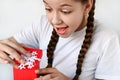 happy, delighted teenage girl with long braids opens beautiful gift box and looks inside. Congratulations on holiday Royalty Free Stock Photo