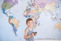 Happy delightful little kid in striped sailor tank top holding vintage film camera on world map background