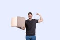 Happy delivery man holding a box package and felxing one hand biceps imagine superpower. Confident courier worker . Personal