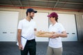 Happy delivery man and woman standing with clipboard and parcel