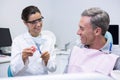 Happy dentist teaching man brushing teeth on dental mold