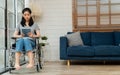 Happy disabled Asian woman sitting in a wheelchair And working with tablet at home, The concept of Technologies for the Royalty Free Stock Photo