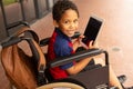 Happy disabled schoolboy with digital tablet looking at camera in corridor