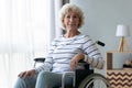 Happy disabled senior grandma sit on wheelchair looking at camera