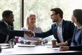 Happy diverse business partners shaking hands over table Royalty Free Stock Photo