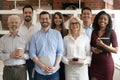 Happy diverse business team standing in office looking at camera